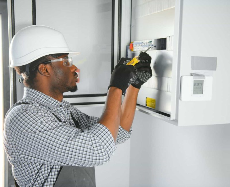 A male electrician works in a switchboard