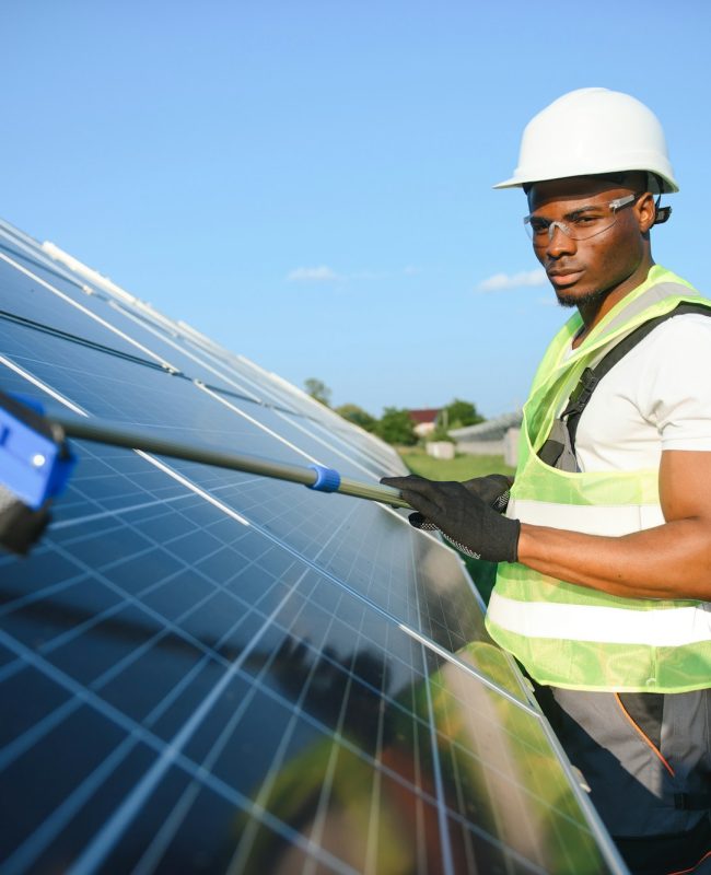 african american worker cleaning solar panel in solar power plant